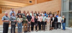 Members of the Ontario Biodiversity Council stand in the lobby of the Toronto and Regional Conservation Authority main office in September of 2025. The photo shows a few dozen people standing in a group smiling and holding tree saplings.
